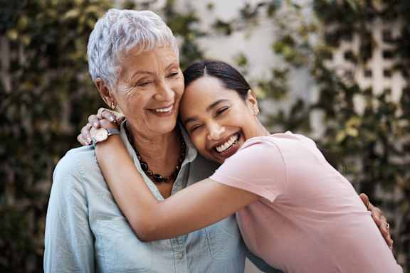 a young woman hugging an older woman and smiling