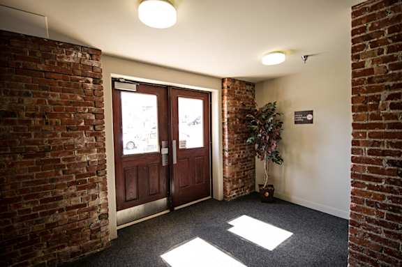 A hallway with a brick wall and a door.
