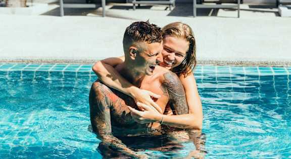 A man and a woman are embracing in a swimming pool.
