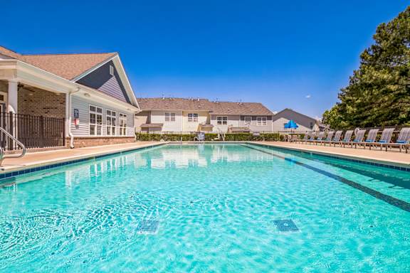 A swimming pool in a residential area with houses in the background.