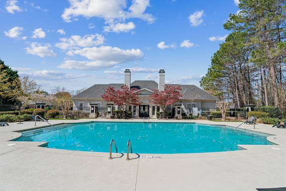 A large swimming pool in front of a house with a chimney.