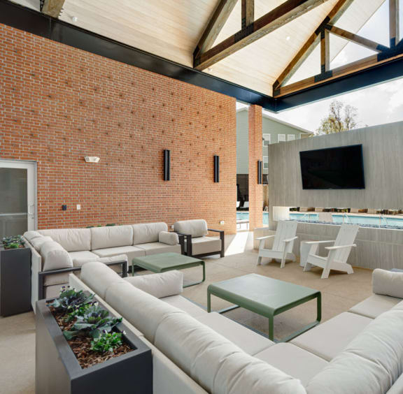 a large living room with white furniture and a brick wall