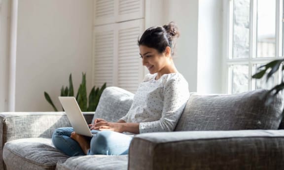 a woman sitting on a couch using a laptop computer