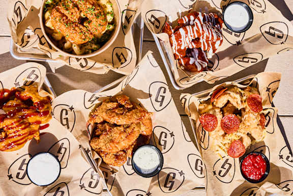 A variety of food including fried chicken, fries, and desserts are served on paper trays.