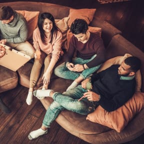 Group of Friends Sitting on Couch Together Having Pizza