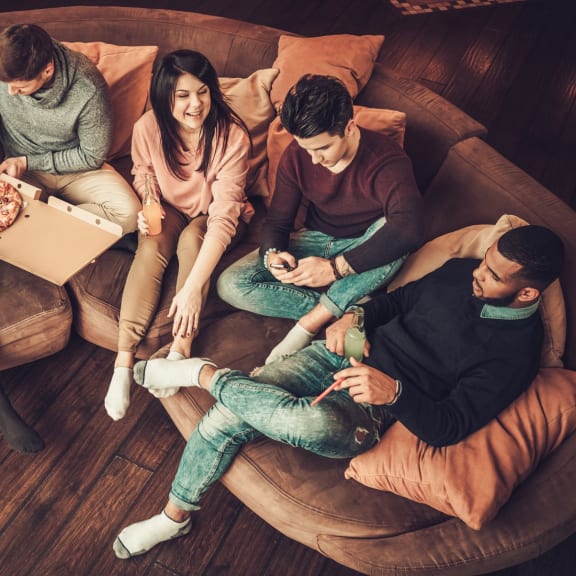 Group of Friends Sitting on Couch Together Having Pizza