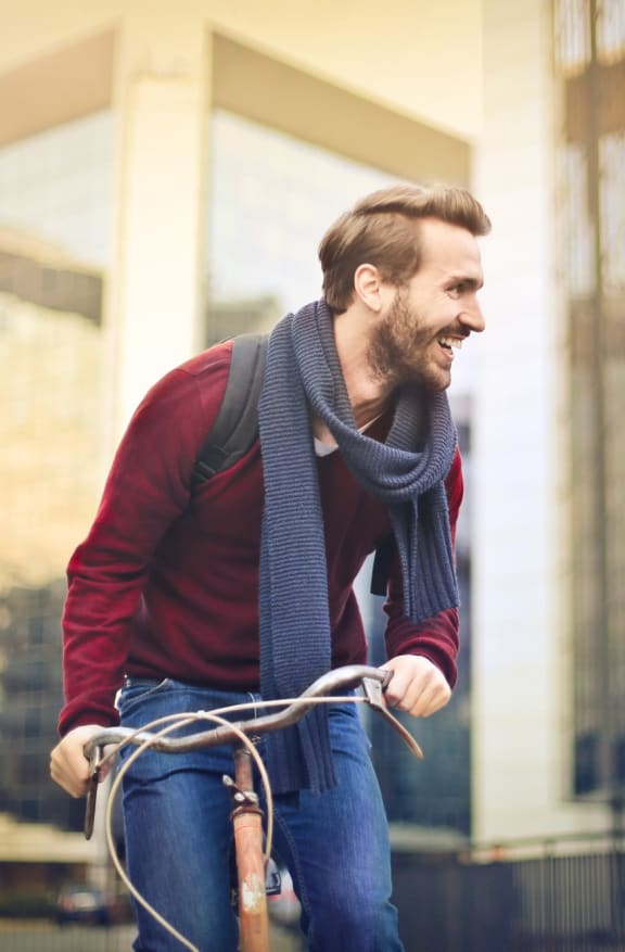 Man with Scarf and Backpack on Bicycle Smiling