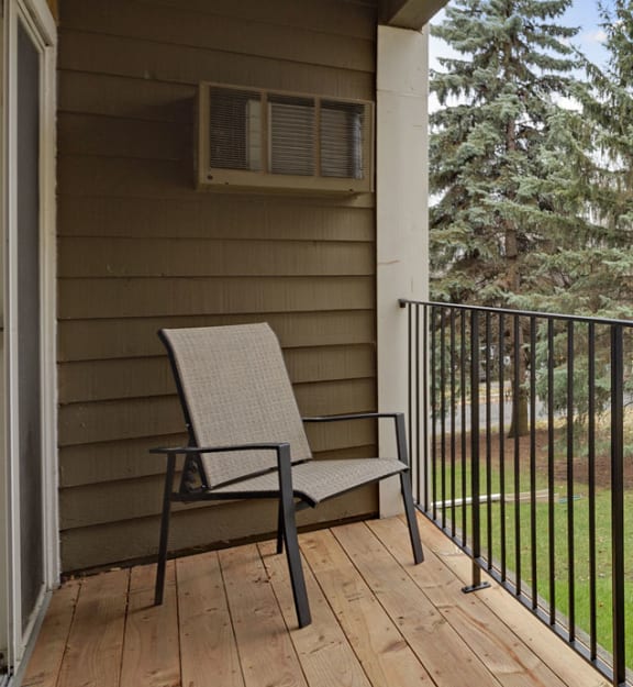 A chair and bench are on a porch with a black railing. at Mallard Creek, Golden Valley, Minnesota