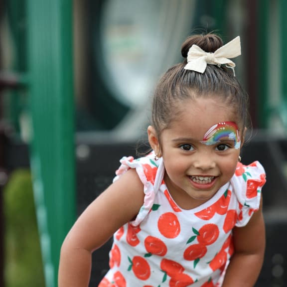 a little girl in a red and white dress holding on to a railing
