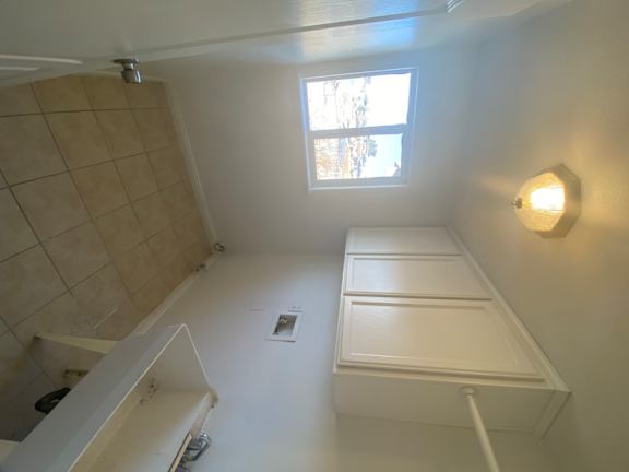 A bathroom with a window and a tiled shower.