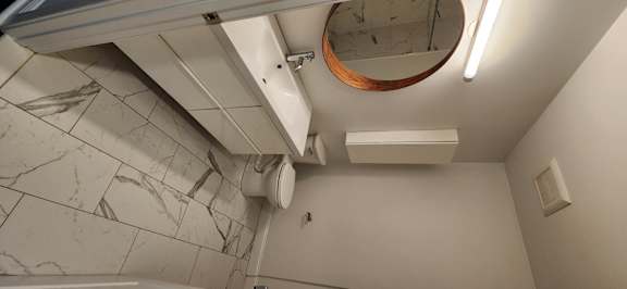 A bathroom with a toilet, sink, and mirror.