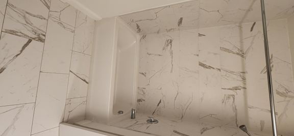 A white marble tiled shower with a white tub.