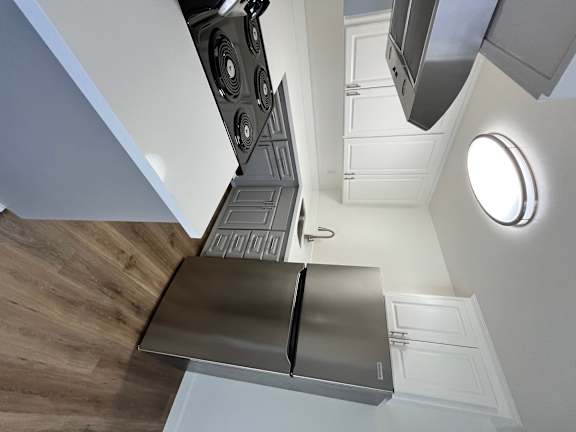 A modern kitchen with a stainless steel refrigerator and a wooden floor.