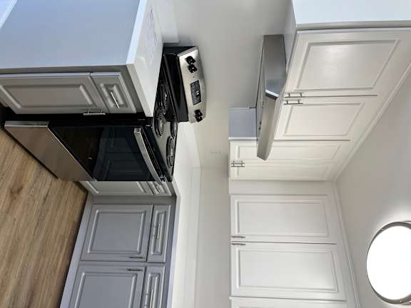 A modern kitchen with white cabinets and a black stove top oven.