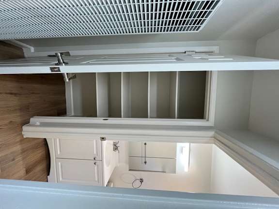 A white refrigerator with its door open and a drain grate at the bottom.