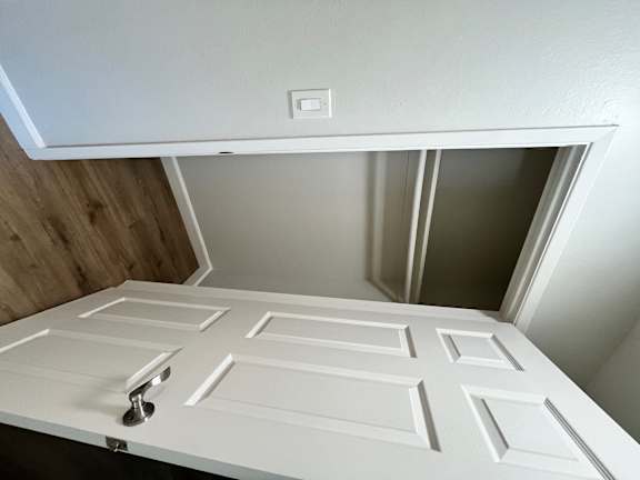 A white ceiling with a light switch and a white door.