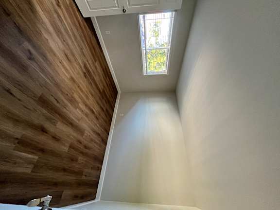 A wooden staircase with a white railing and a small window with a view of trees.