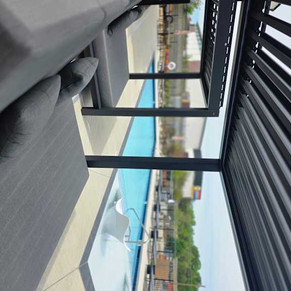A black metal railing with a grey cushion on the right side.