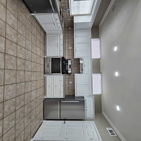 A kitchen with white cabinets and a black counter top.