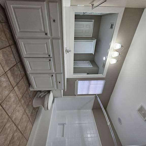 A bathroom with a toilet, sink, and mirror.