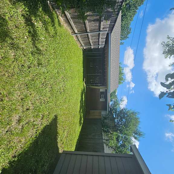 A house with a wooden deck and a green lawn.