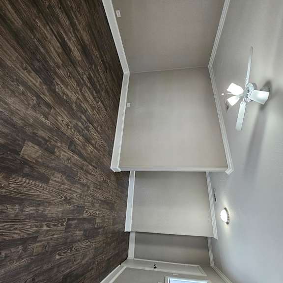 A small room with a ceiling fan and a wooden wall.