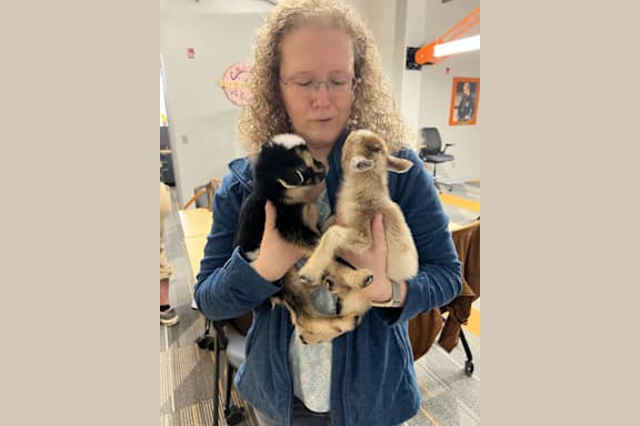 a woman holding two newborn kittens in her lap