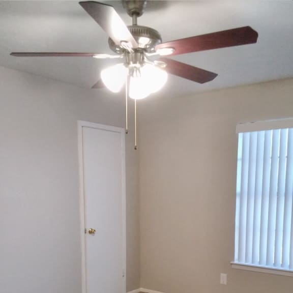 the bottom of a room with a ceiling fan and a closet