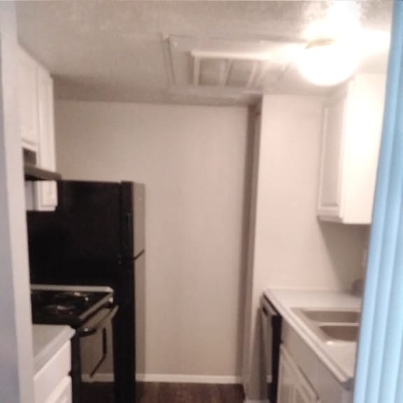 a small kitchen with a wood accent wall and a black stove