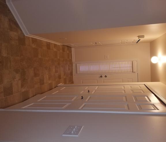 A room with a brown tiled wall and a white ceiling.