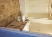 Thumbnail 12 of 41 - A bathroom with a toilet and a tiled wall.