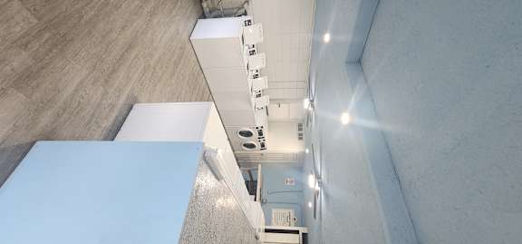 A long white table is in a room with a concrete wall.