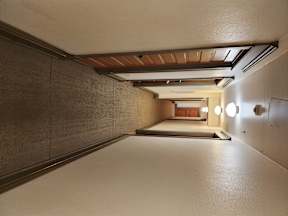 A long hallway with a brown floor and white walls.