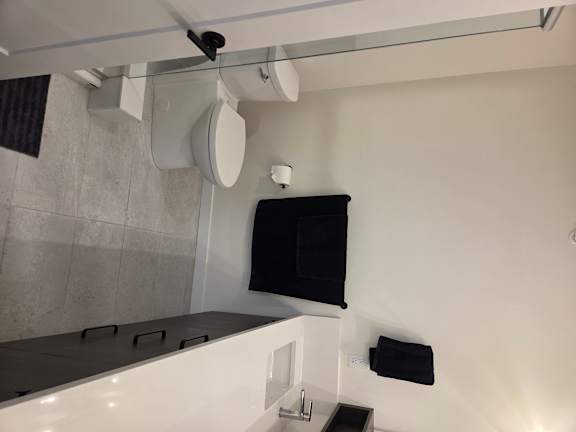 A bathroom with a toilet, sink, and a monitor on the wall.