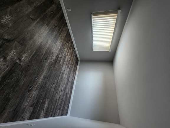 a window with blinds in a room with a whitewall