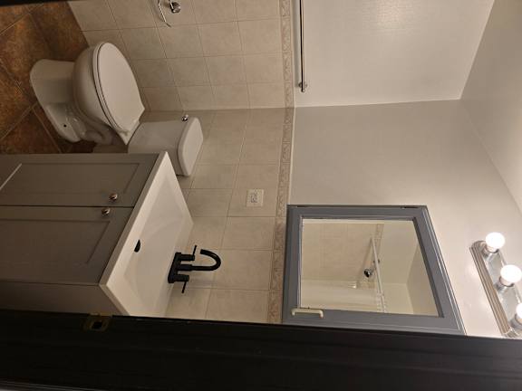 A bathroom with a toilet, sink, and mirror.
