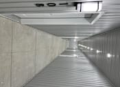 Thumbnail 2 of 7 - A long, narrow corridor with a metal roof and concrete walls.