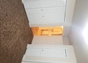 Thumbnail 13 of 41 - A white cabinet with drawers is in the foreground with a brown carpeted floor.