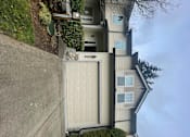 Thumbnail 55 of 82 - A house with a grey garage door and a brown roof.