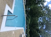 Thumbnail 26 of 29 - A pool with a diving board and a metal ladder.