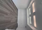 Thumbnail 14 of 24 - Live Work Apartments for Rent in Corona, CA - Dos Lagos Townhomes - Empty Room With Gray Wood-Style Flooring, White Walls, Overhead Fluorescent Lighting, And A Closed Door.