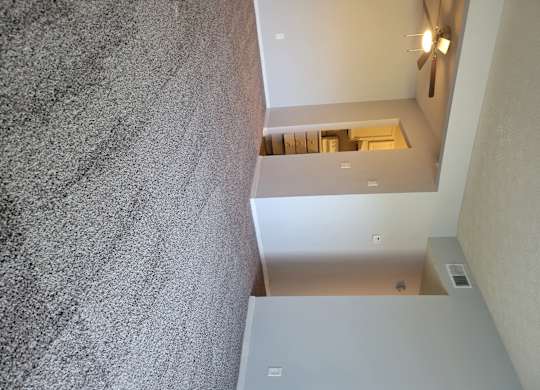 A wall with a grey texture and a ceiling with lights.