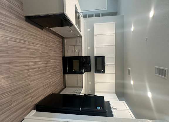 A modern kitchen with black appliances and white cabinets.