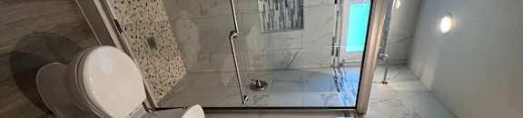 View of bathroom with walk in tile shower, well lit window above, toilet, and sink