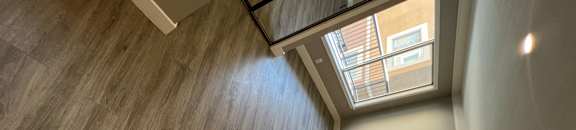 View into living room with wood look flooring, recessed lighting, and well lit almost floor to ceiling window