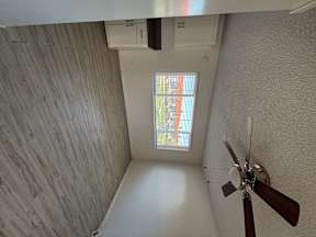 A ceiling fan hangs over a white table in a room with a window.