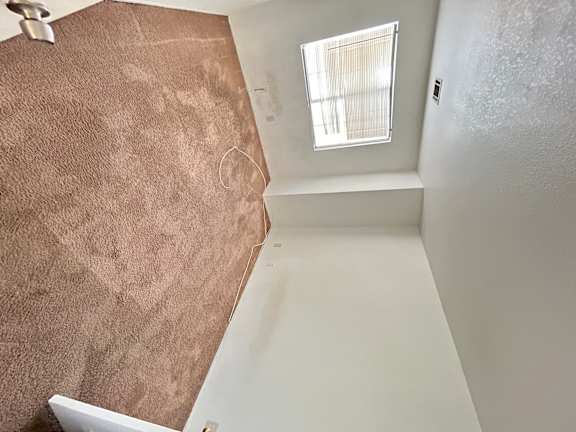 A small window in a room with a brown carpet.