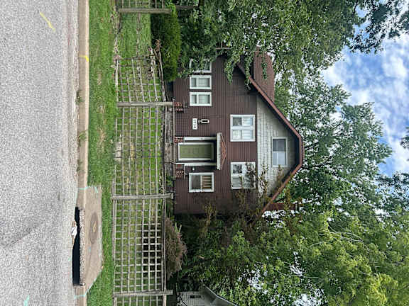 A house with a brown roof and white windows is surrounded by trees.