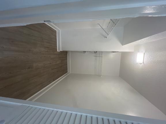 A white room with a wooden floor and a staircase.