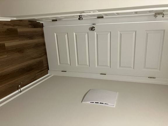 A white kitchen cabinet with a vent above it.